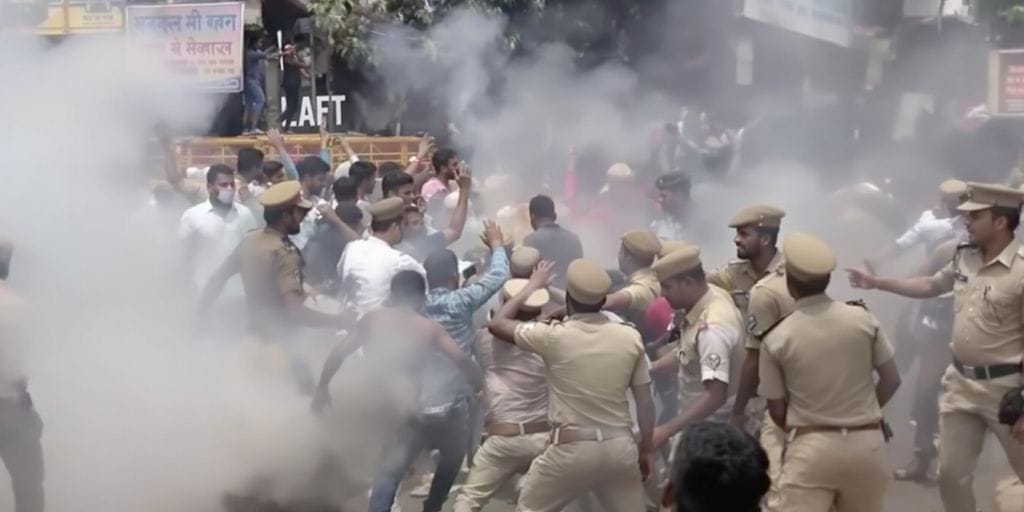 Students protesting in Bihar amid police presence and smoke.